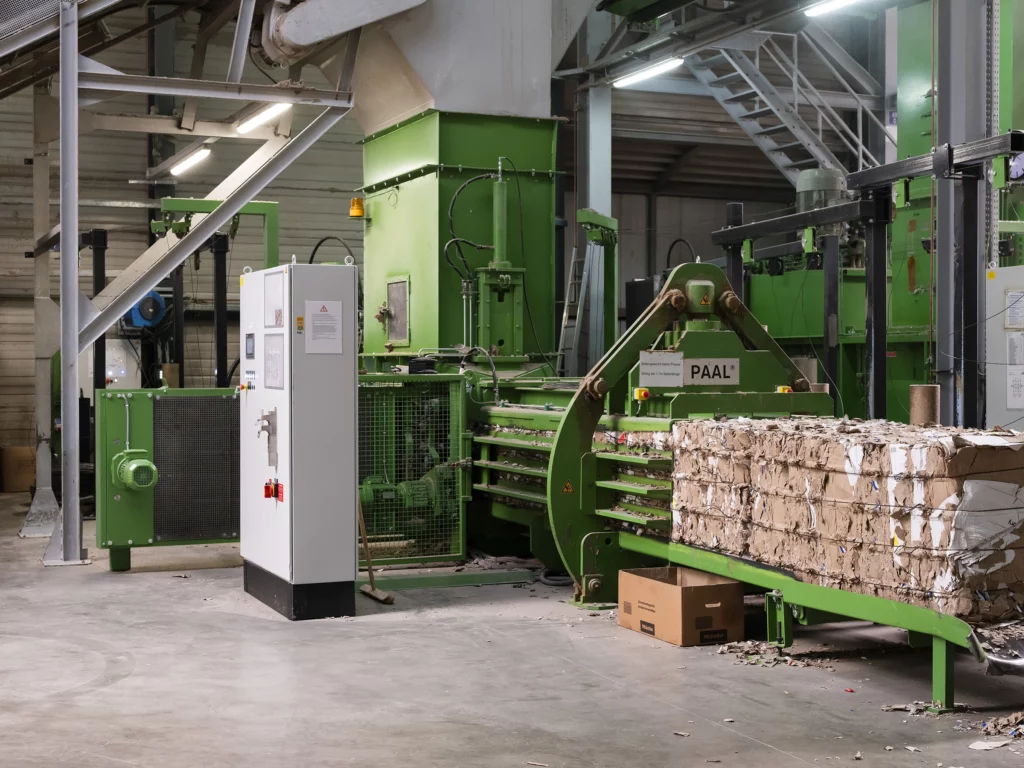Industrielle Papierpresse mit gepressten Kartonstapeln.
